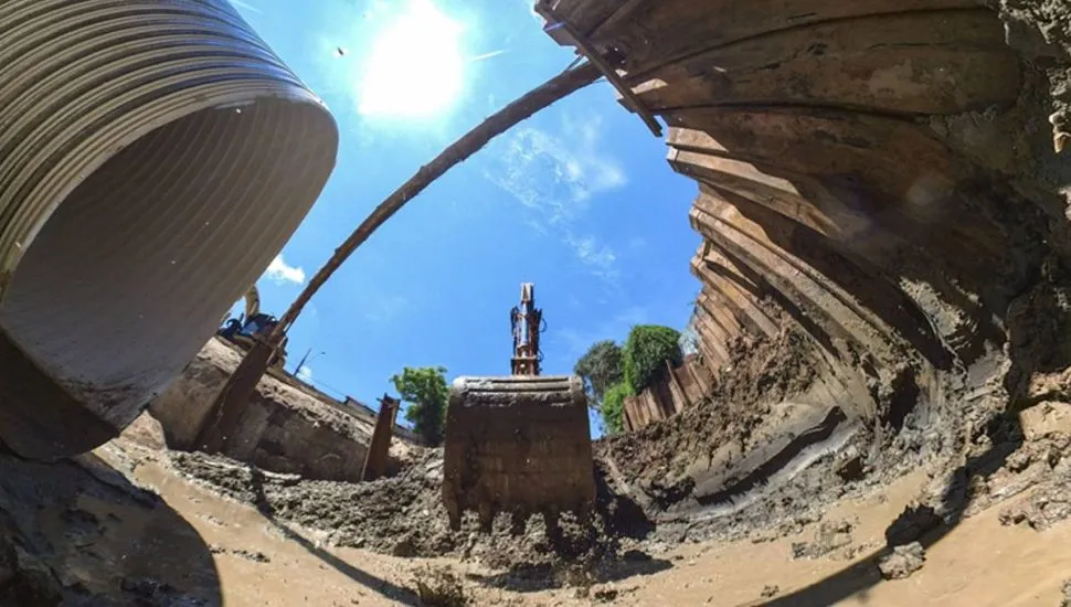 Imagem mostra uma obra em Curitiba com máquinas escavadeiras, buracos e manilhas gigantes.