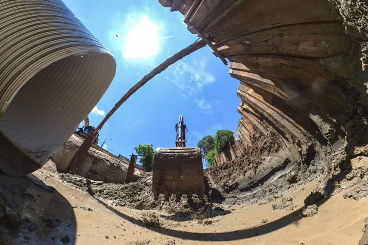 Imagem mostra uma obra em Curitiba com máquinas escavadeiras, buracos e manilhas gigantes.