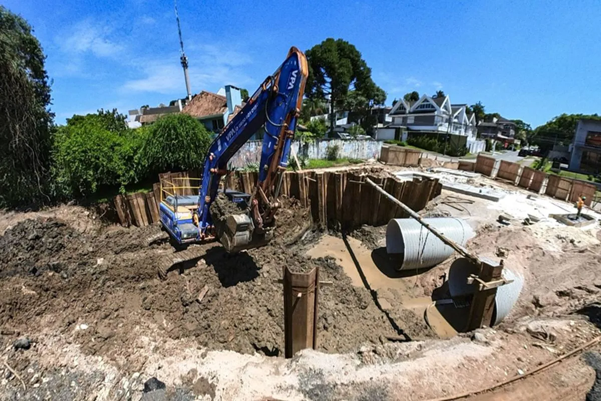 Imagem mostra uma obra em Curitiba com máquinas escavadeiras, buracos e manilhas gigantes.