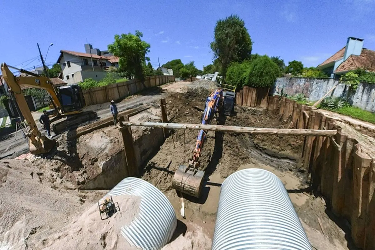 Imagem mostra uma obra em Curitiba com máquinas escavadeiras, buracos e manilhas gigantes.