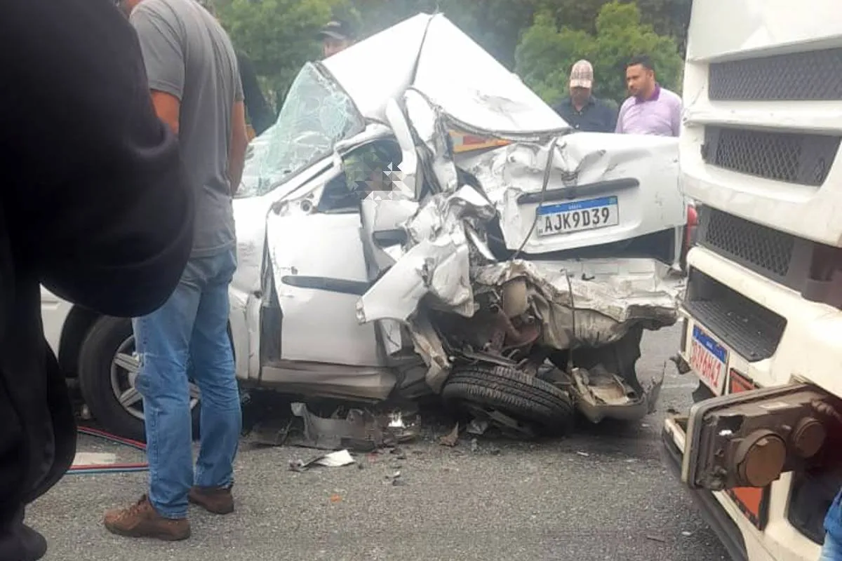 Imagem mostra um carro destruído, prensado entre caminhões.