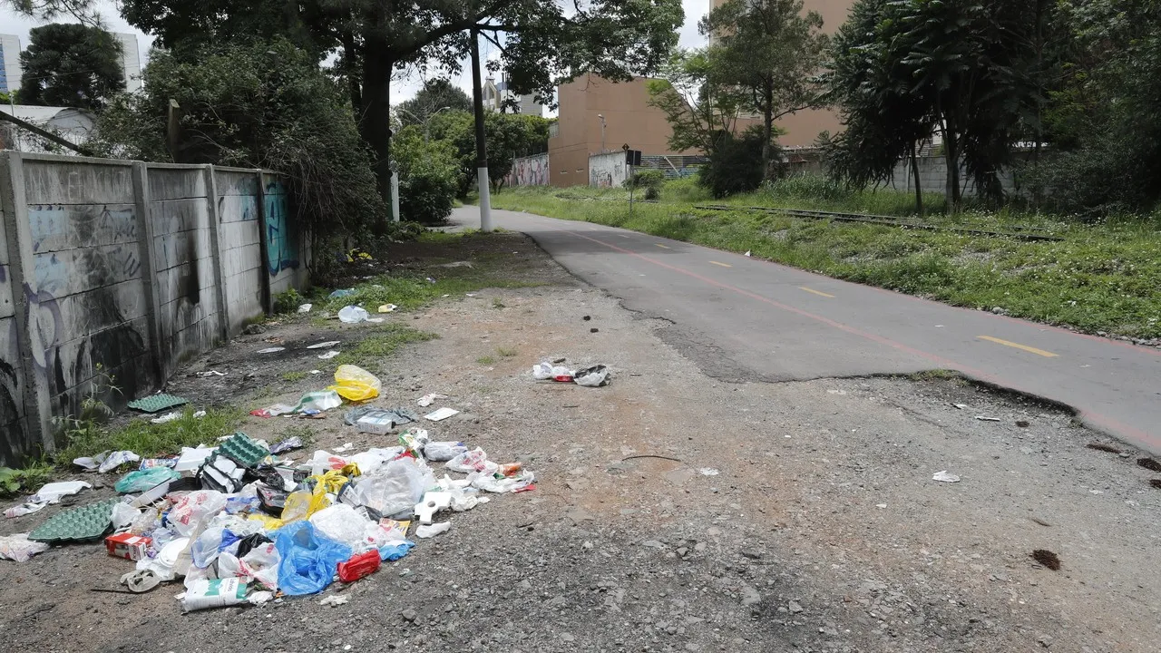 Ciclovia em Curitiba sem manutenção: acúmulo de lixo e sinalização confusa.