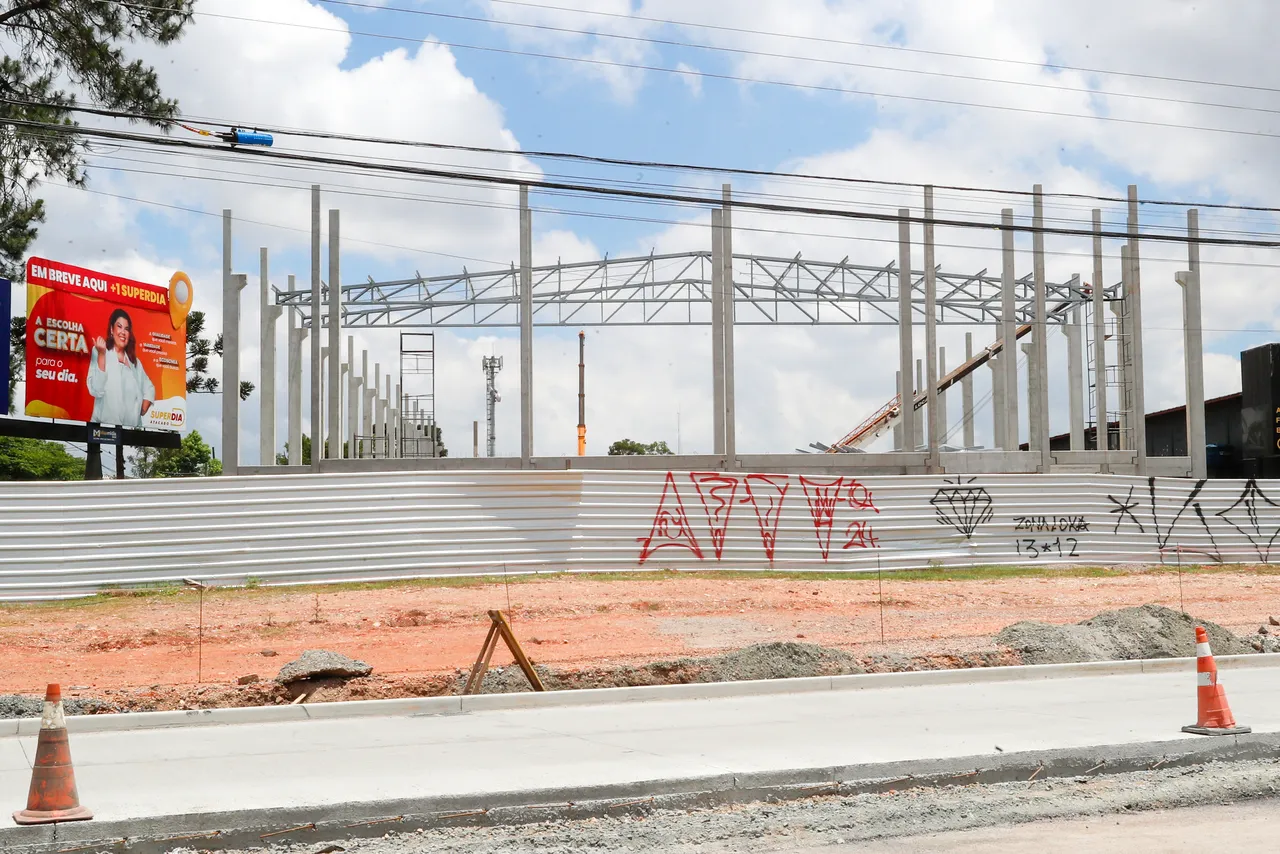 imagem mostra, a partir da visão de quem está na rua, a estrutura que está sendo erguida em colunas pré moldadas para a construção do supermercado