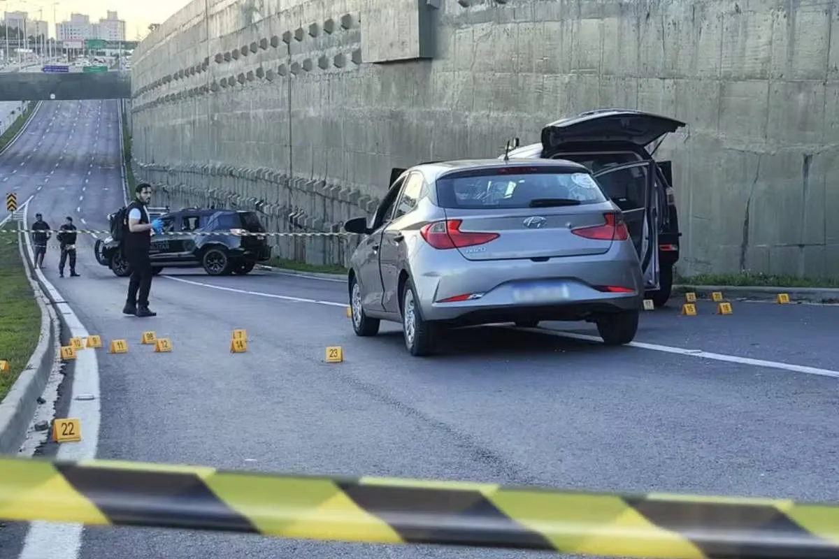 Imagem mostra um carro prata, com faixas de isolamento.