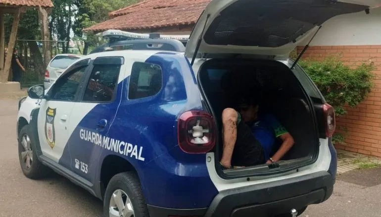 Imagem mostra um homem dentro de uma viatura da Guarda Municipal de Curitiba.