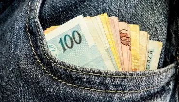 Na imagem, notas de real dentro de um bolso de calça jeans