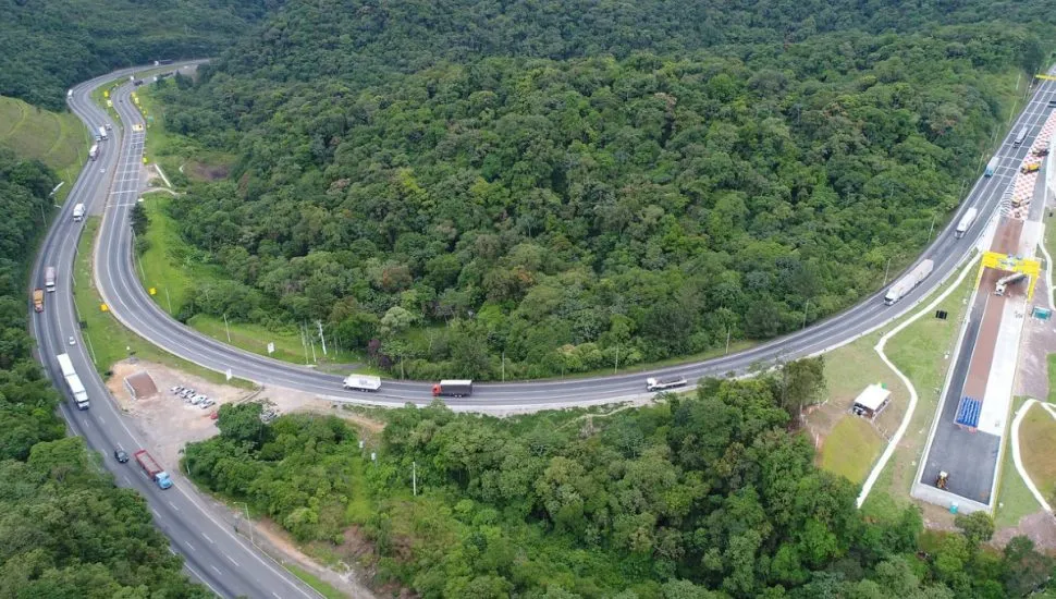 Imagem aérea da BR-376, com caminhões, rodovia e vegetação