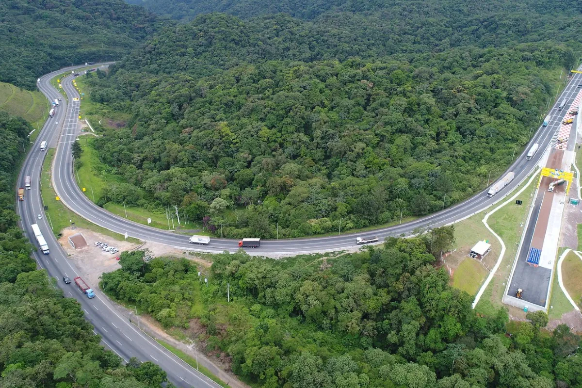 Imagem aérea da BR-376, com caminhões, rodovia e vegetação