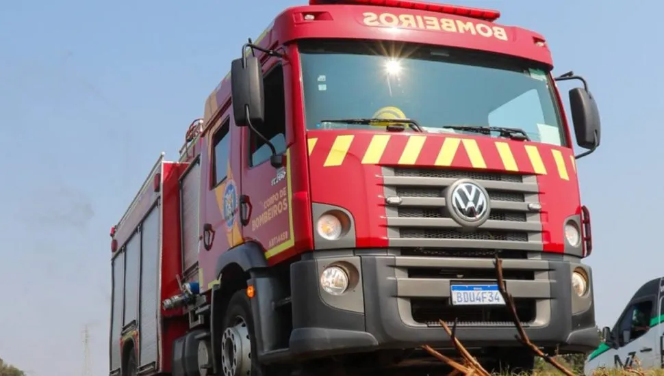 Imagem mostra um caminhão do Corpo de Bombeiros e um céu azul ao fundo.