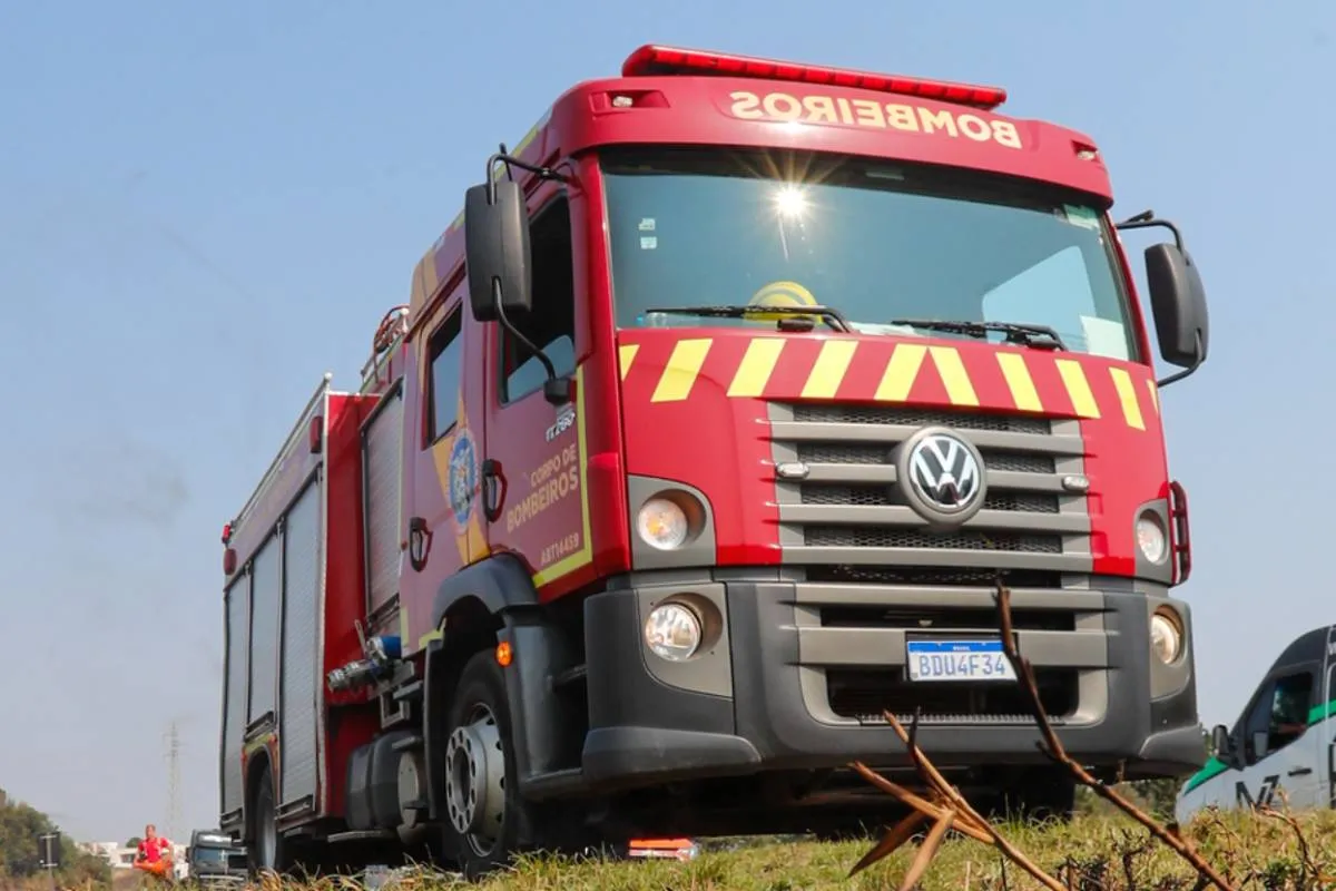 Imagem mostra um caminhão do Corpo de Bombeiros e um céu azul ao fundo.