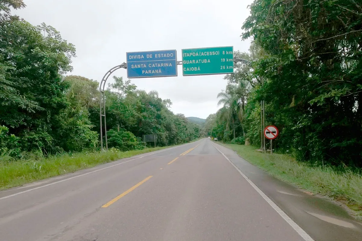 Na imagem, rodovia PR-412, com placa da divisa entre os estados do Paraná e Santa Catarina