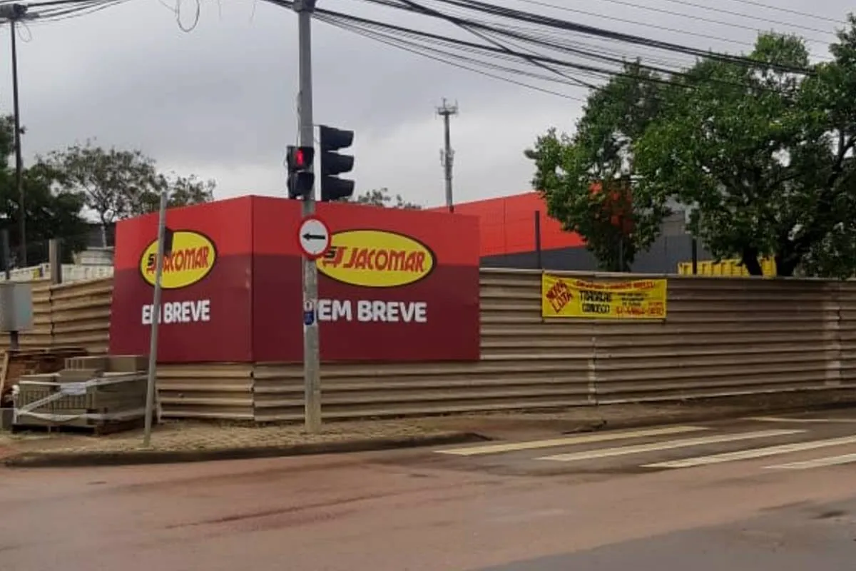 Imagem mostra um terreno com tapumes e a placa do novo Jacomar.