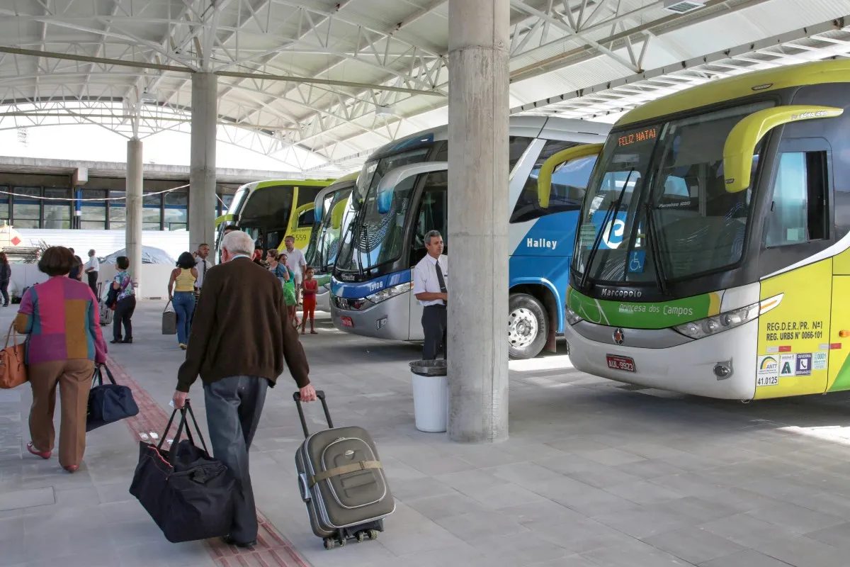 Na imagem, ônibus e passageiros na rodoviária