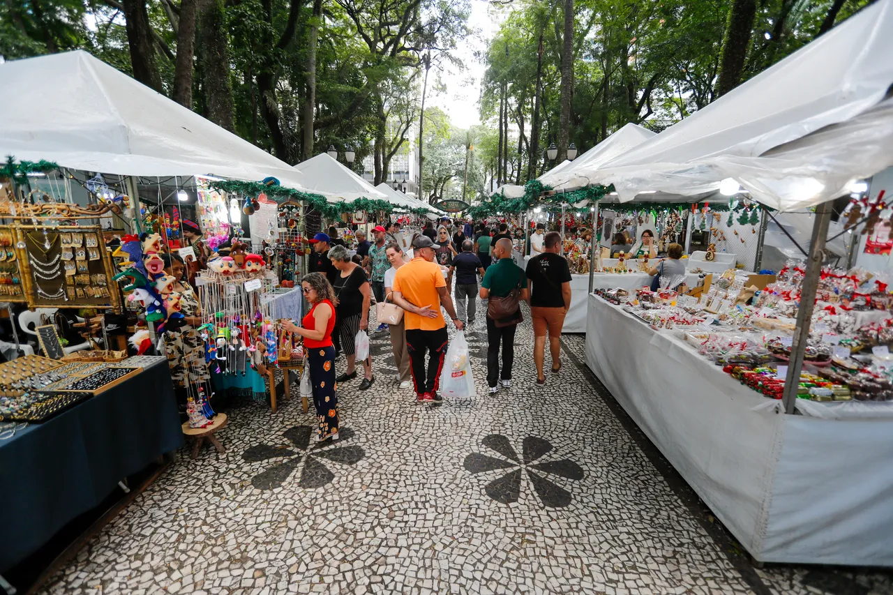 Na imagem, pessoas passeiam e fazem compras na feirinha de Natal em Curitiba