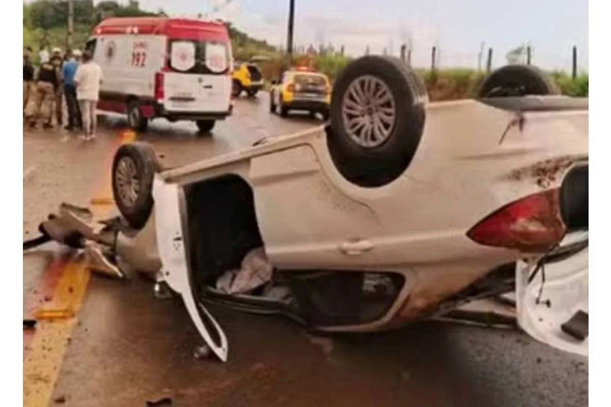 Imagem mostra um carro branco capotado.