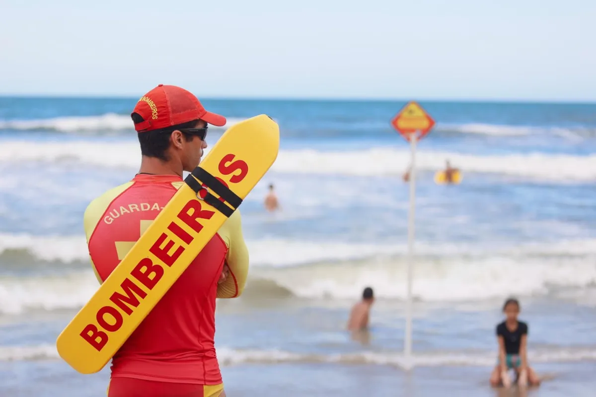 Na imagem, um bombeiro, de costas, monitora banhistas em praia do Paraná