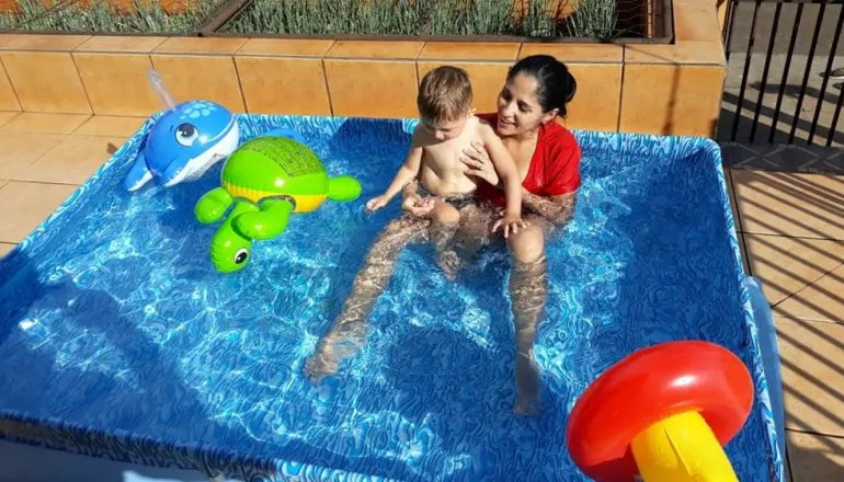 Na imagem, piscina de plástico, criança e mãe