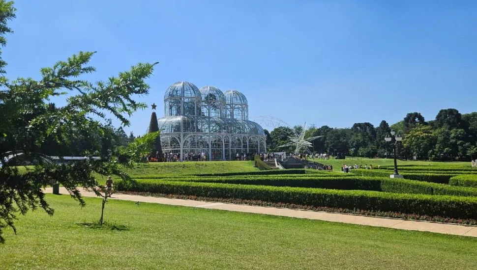 Imagem mostra o Jardim Botânico, em Curitiba, com céu azul.