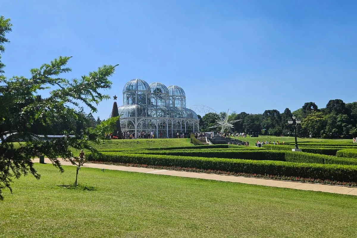 Imagem mostra o Jardim Botânico, em Curitiba, com céu azul.