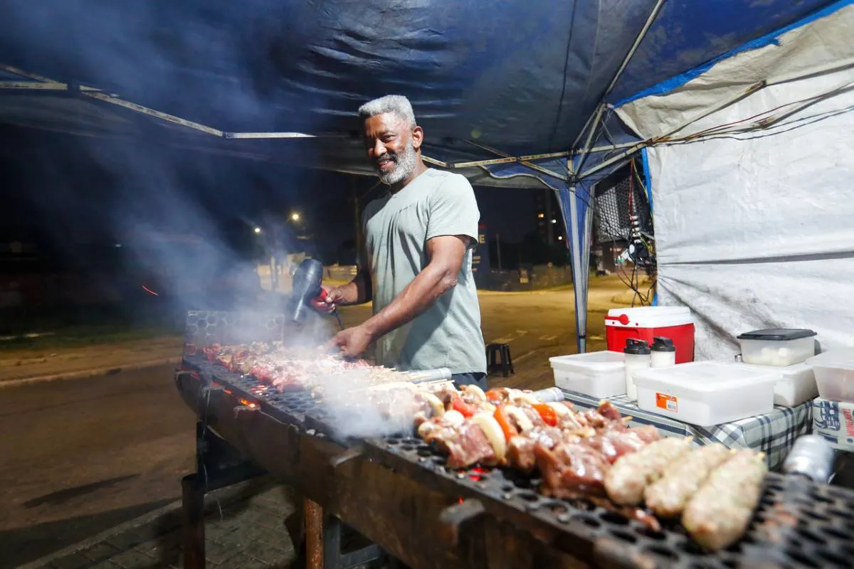 Imagem mostra uma barraca de espetinho com vários espetinhos de diferentes "sabores" na grelha.