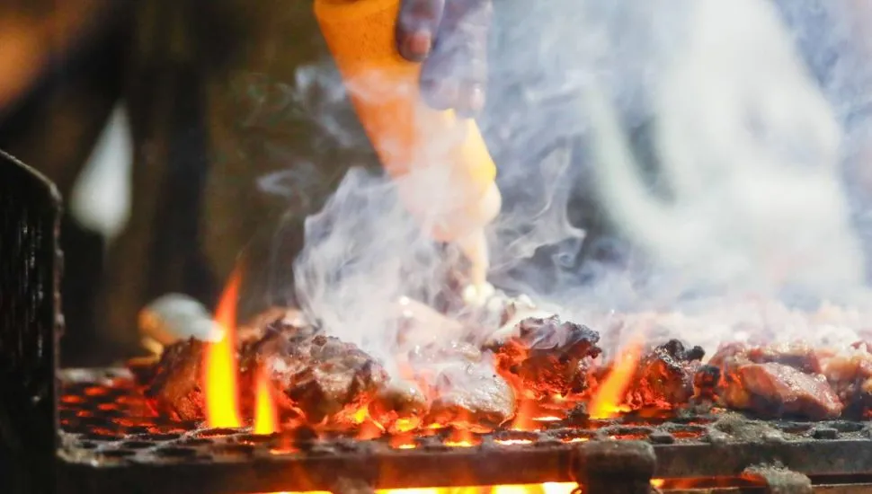 Imagem mostra uma barraca de espetinho com vários espetinhos de diferentes "sabores" na grelha.