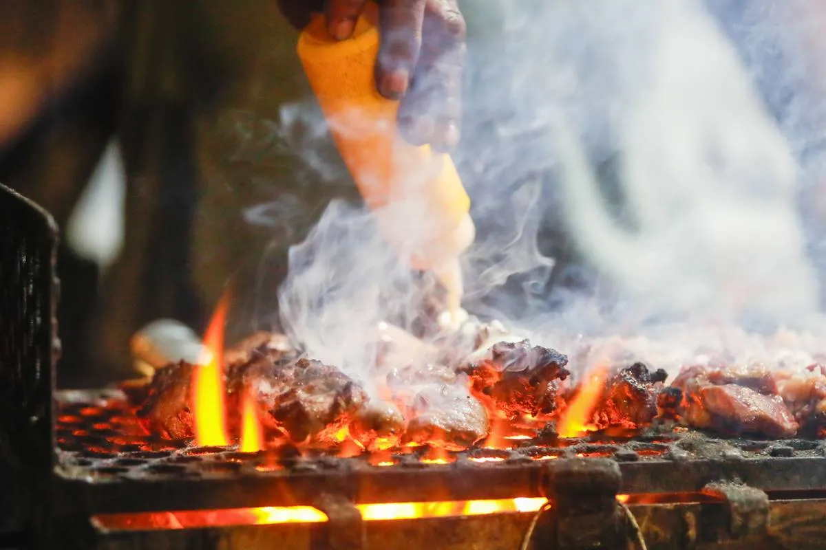 Imagem mostra uma barraca de espetinho com vários espetinhos de diferentes "sabores" na grelha.