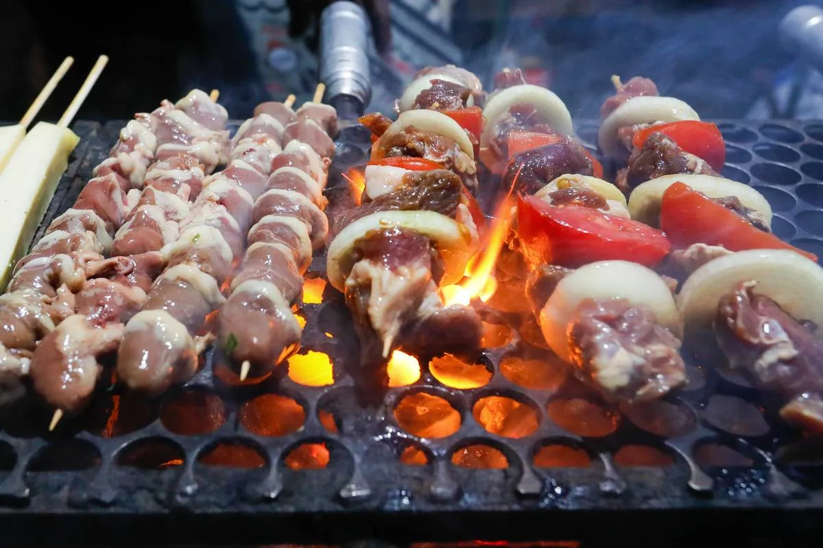 Imagem mostra uma barraca de espetinho com vários espetinhos de diferentes "sabores" na grelha.