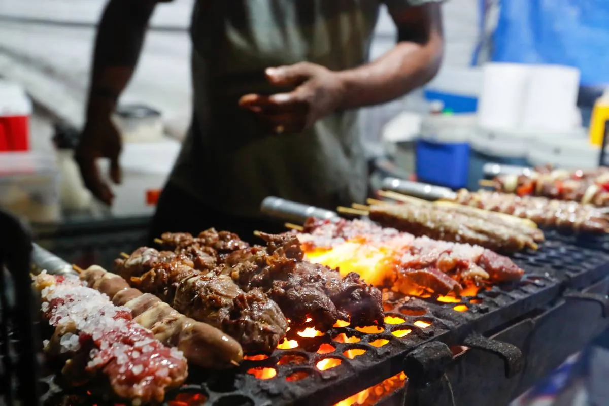 Imagem mostra uma barraca de espetinho com vários espetinhos de diferentes "sabores" na grelha.