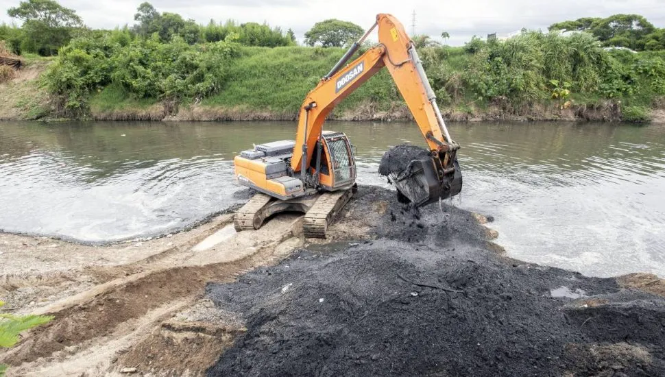 Imagem mostra uma máquina limpando um rio