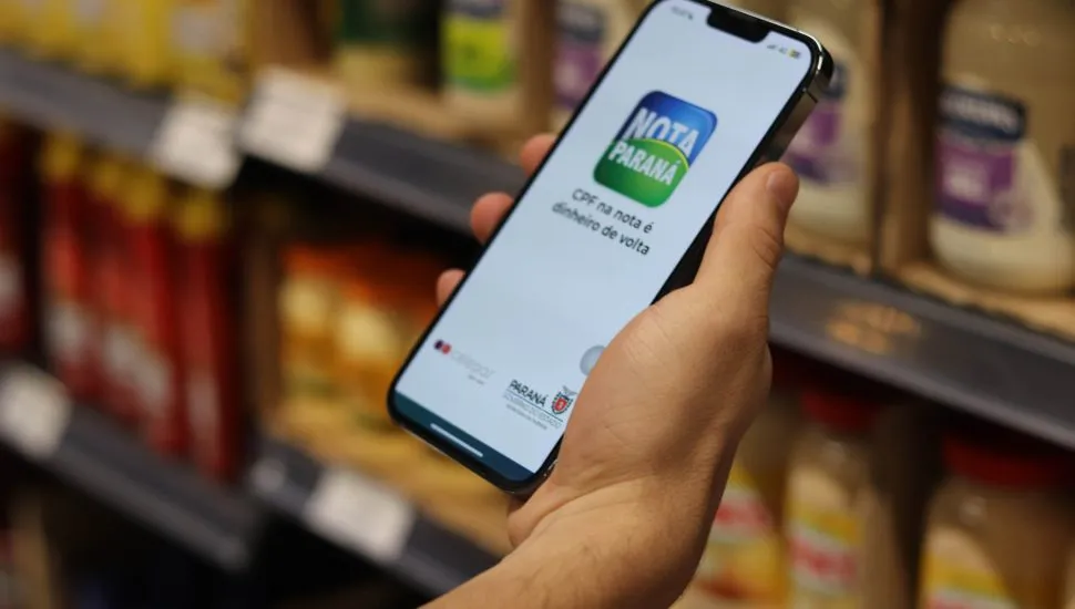 Pessoa segurando celular com aplicativo do Nota Paraná aberto