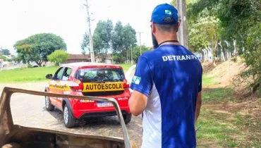 Imagem mostra instrutor do Detran-PR observando carro de autoescola