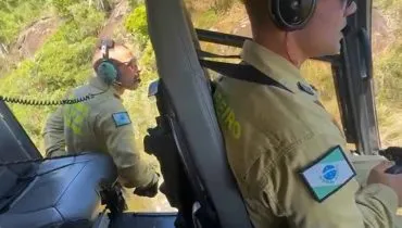 Imagem mostra bombeiros em regate de helicóptero.