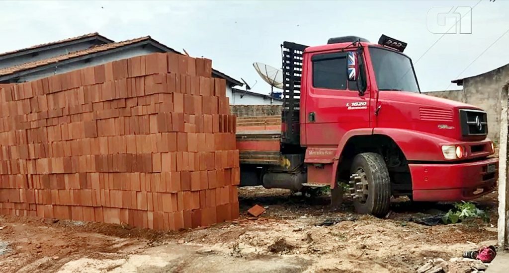 Motorista e ajudante descarregam carga de tijolo e deixam caminhão preso no terreno