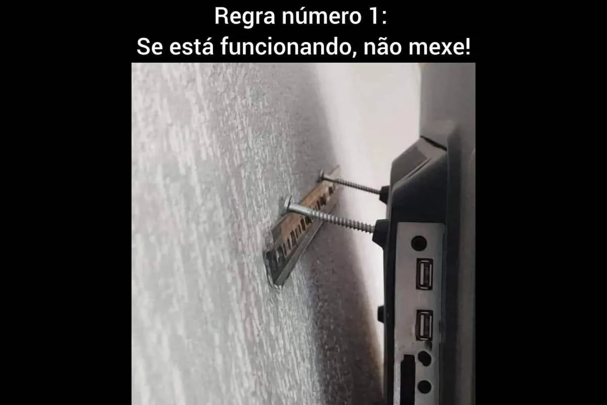 Imagem mostra uma televisão sendo equilibrada por dois parafusos com a frase: Regra número 1: Se está funcionando não mexa!