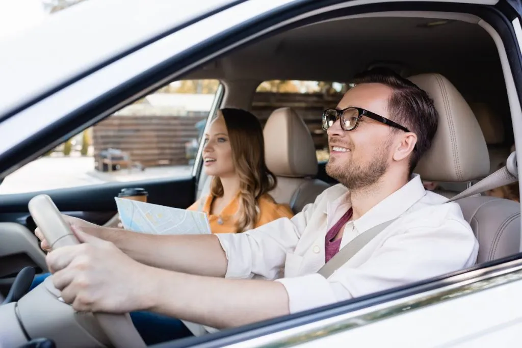 Imagem mostra um homem e uma mulher andando de carro