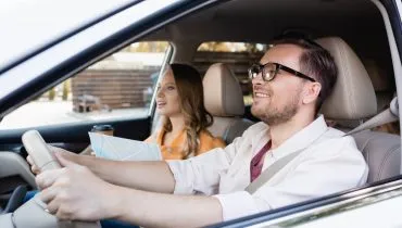 Imagem mostra um homem e uma mulher andando de carro