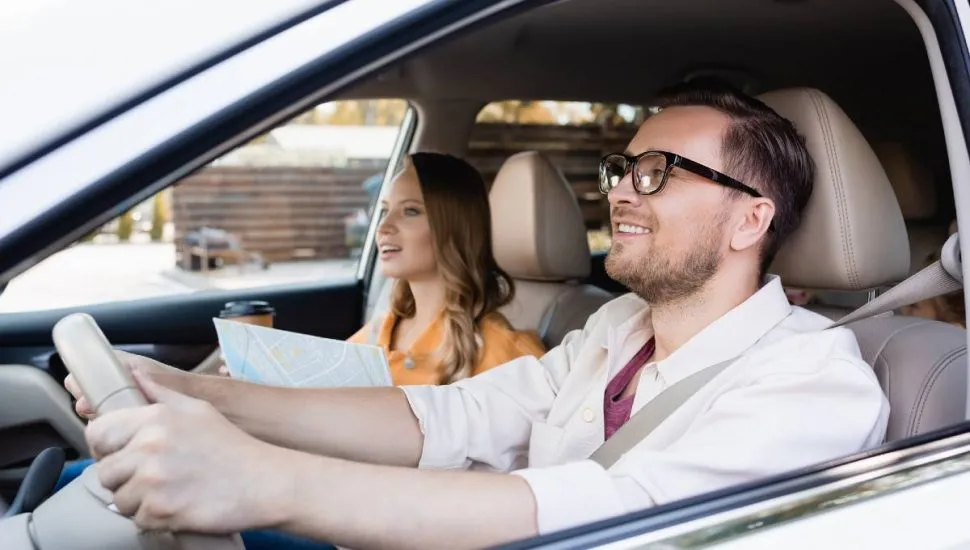 Imagem mostra um homem e uma mulher andando de carro