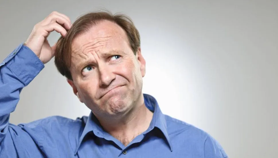 Imagem mostra um homem com uma camisa azul coçando a cabeça.