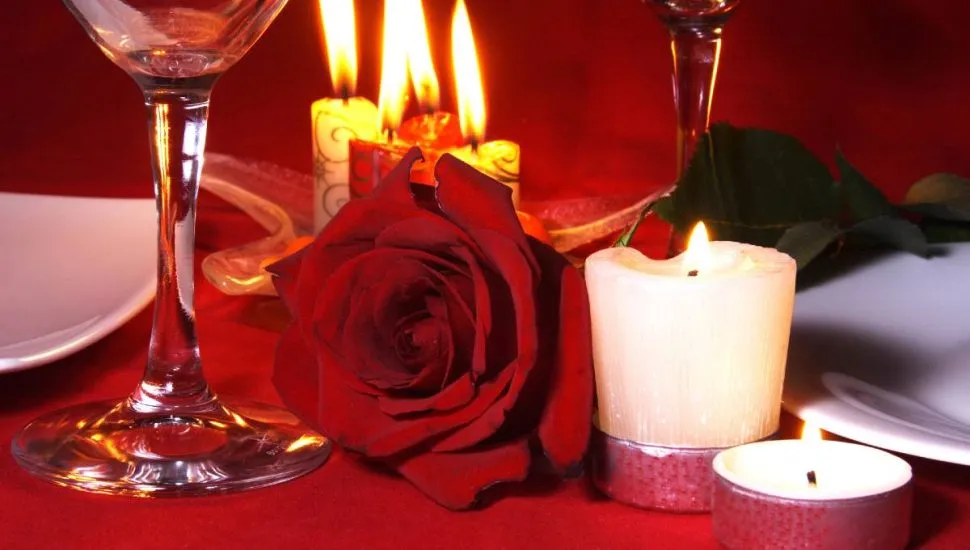 Imagem mostra uma decoração com rosas, velas e vinho.