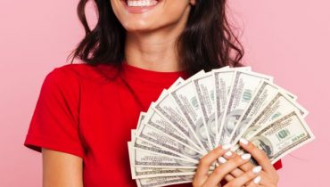 Smiling brunette woman holding money in hands