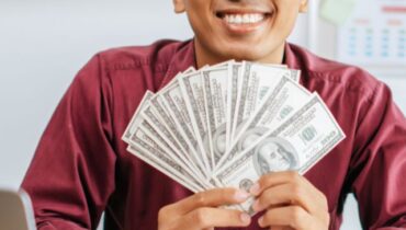 a man working in an office and holding money.