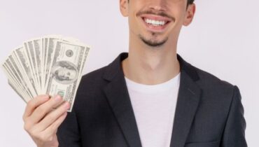 Portrait of a cheerful man holding dollar bills over white backg