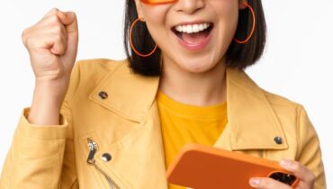 Image of stylish korean girl dancing with smartphone, laughing happy and smiling, standing over white background