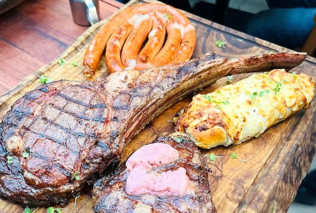 Foto mostra alguns dos cortes oferecidos pela casa, como o tomahawk, linguicinha, e pão de alho