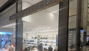 Imagem mostra a vitrine de uma loja da grife Jorge Bischoff. Vários sapatos e bolsas estão em destaque por trás do vidro