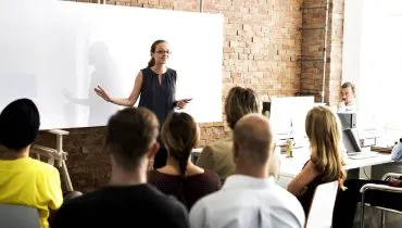 Imagem mostra uma mulher liderando uma equipe.